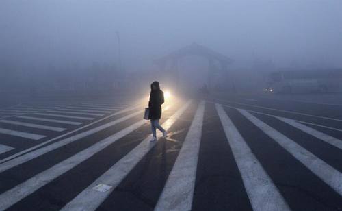 девушка в пальто с пакетом в свете фар в туман на дороге