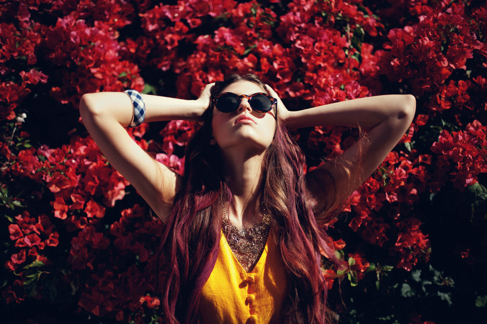девушка в солнечных очках среди красных цветов