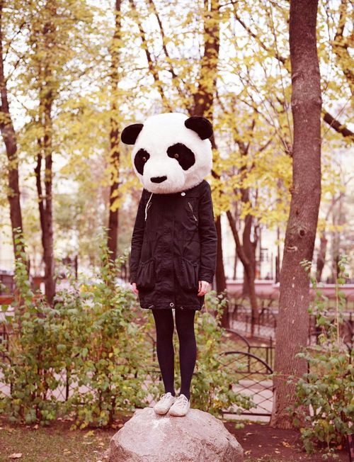девушка в маске панды стоит на камне