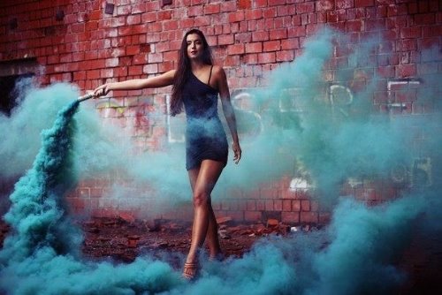 девушка у стены с синим дымом