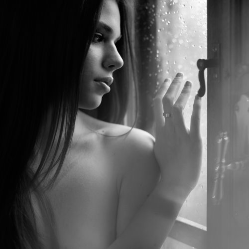 девушка смотрит на капли дождя на окне
