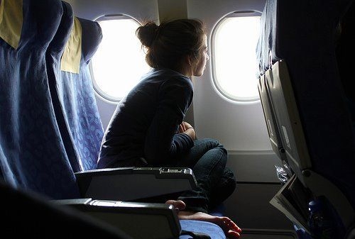 девушка с пучком в профиль сидит у окна самолета