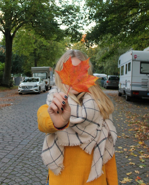 блондинка с черными ногтями прикрылась оранжевым кленовым листочком не видно лица