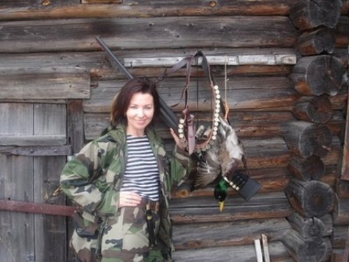 девушка охотница убила утку возле деревянного дома