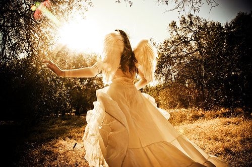 девушка в длинном пышном белом платье со спины с крыльями ангела бежит к солнцу идеи для фотосессии в лесу