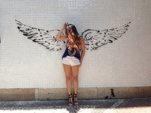 девушка у стены на которой нарисованы крылья ангела