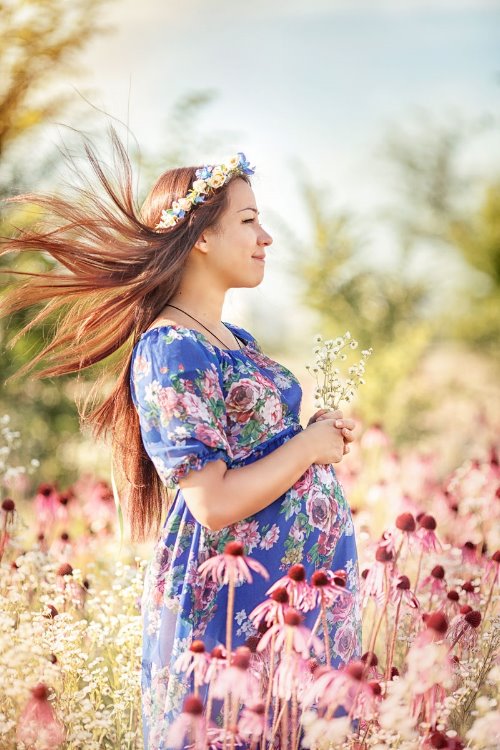 беременная русая девушка в синем платье среди цветов