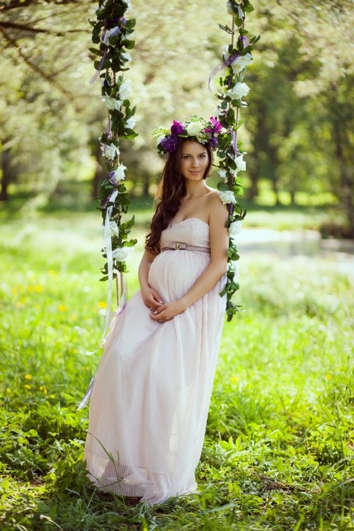 беременная на качелях украшенных цветами