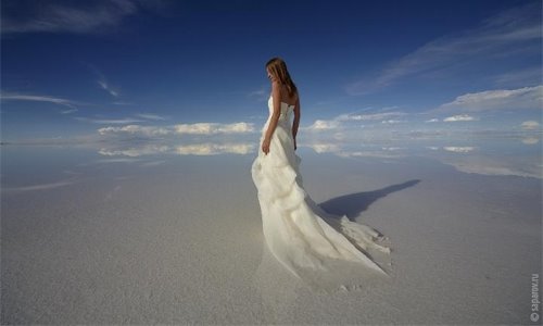 девушка в длинном белом платье со спины на соляном озере в Боливии