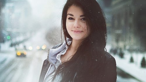 девушка с темным волосом позирует в снежную погоду на дороге