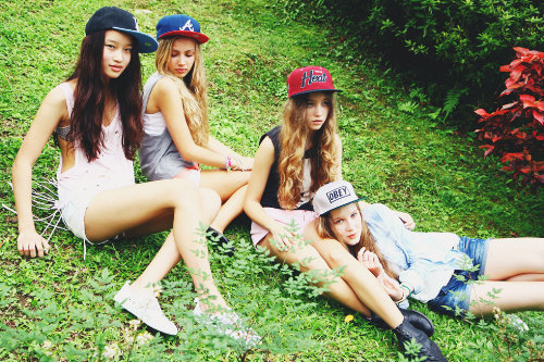 четыре подружки в кепках сидят на траве