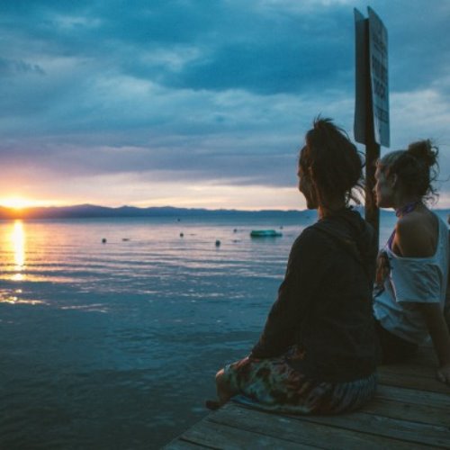 две подруги смотрят на закат солнца на море