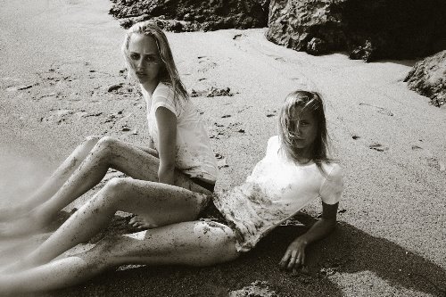 две грязные девушки на берегу моря в белых футболках
