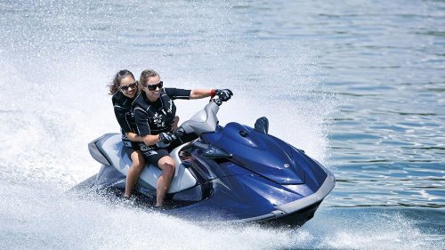 две девушки в гидрокостюмах катаются на водном скутере