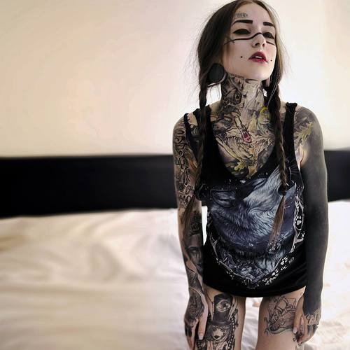девушка вся в татуировках стоит на коленях на кровати квадратное фото
