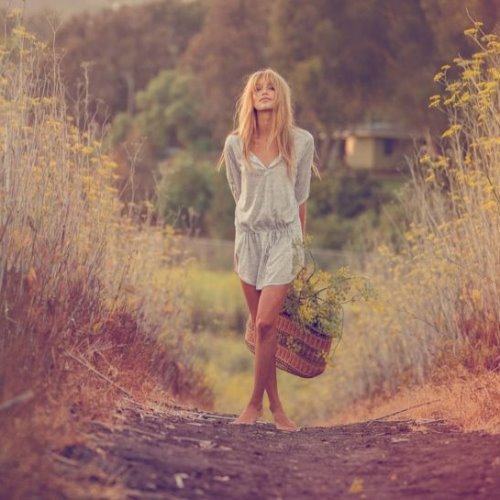 девушка в комбинезоне с корзиной собранных цветов в поле