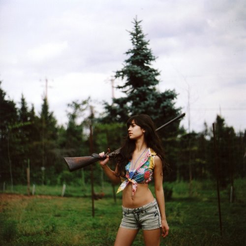 девушка с плоским животиком с ружьем в лесу