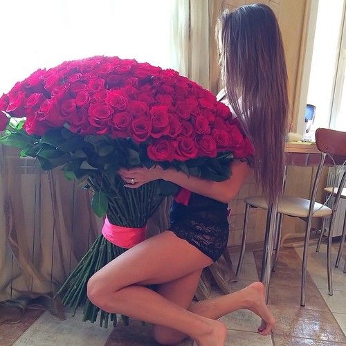 девушка в нижнем белье на кухне с огромным букетом красных роз не видно лица за волосами