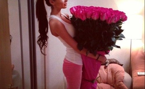 девушка в розовых спортивках с букетом розовых роз в комнате