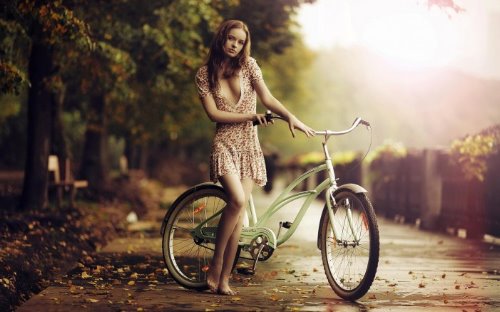 девушка в парке с велосипедом в платье с глубоким декольте в мелкий цветочек