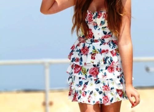 девушка на пляже в ярком летнем платье в цветочек позитивное фото
