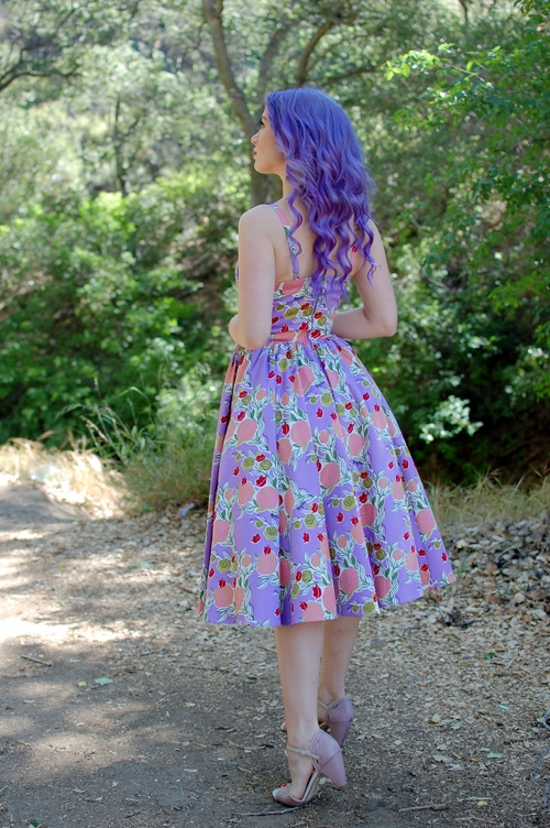 девушка с фиолетовыми волосами со спины в платье с розовыми цветами летом в тени