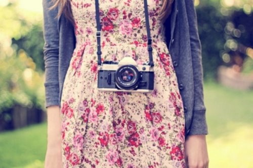 девушка с фотоаппаратом на шее в платье в цветочек и кофточке