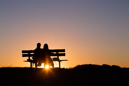 силуэт пары на скамейке на заходе солнца вечером