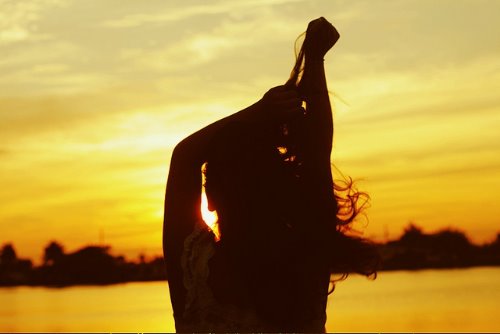 девушка смотрит на закат солнца на море