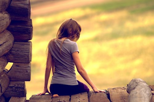 фото девушки со спины сидящей на деревянной крыше