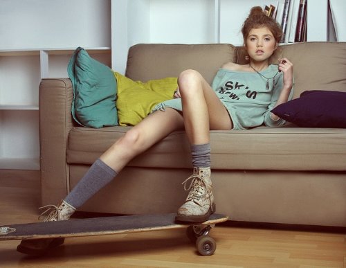 девушка сидит на диване ноги на скейте