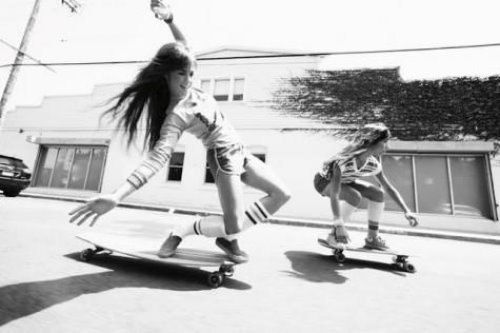 две девушки весело катаются на скейтах