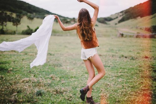 девушка кружит на поляне с шарфом в руке