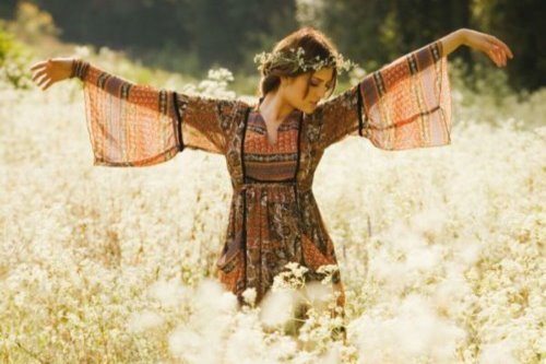 девушка в платье с длинным рукавом танцует в поле белых цветов