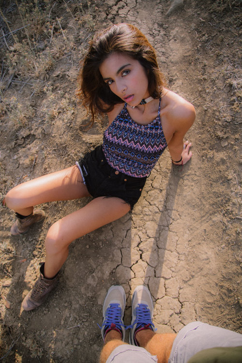 девушка в коротеньких шортиках сидит на потрескавшей земле