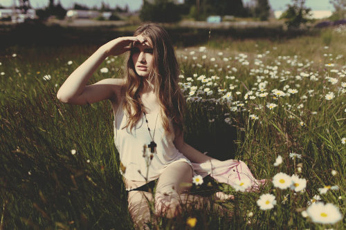 девушка всматривается вдаль сидя в траве