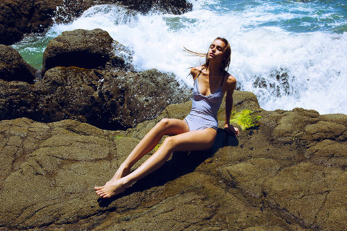 девушка загорает сидя на каменном берегу моря