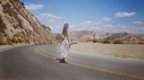 девушка в изысканном платье со спины стоит на дороге на сплошной двойной полосе