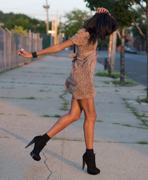 шатенка в коротком летнем платье прыгает по тротуару