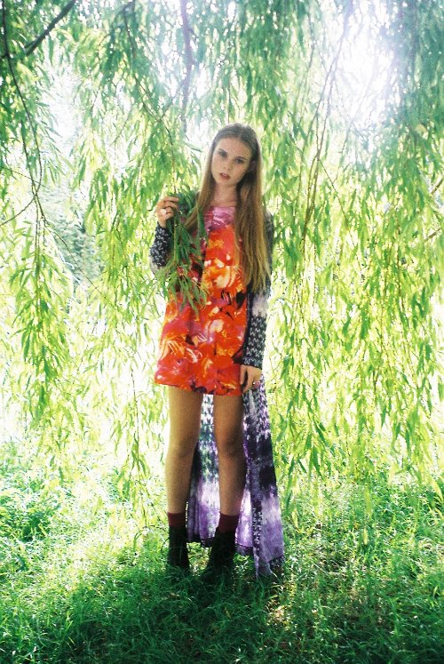 девушка с длинными волосами стоит среди листьев ивы