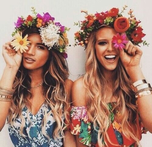 две девушки в венках из цветов весело фотографируются