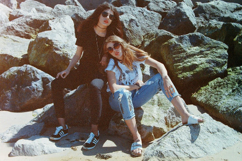 две девушки в солнцезащитных очках сидят на камнях