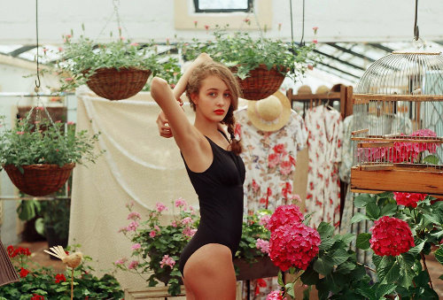 девушка в черном купальнике в цветочной оранжерее