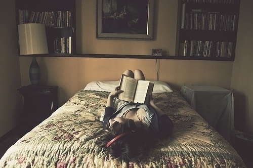 девушка в спальне лежит на спине держа книгу