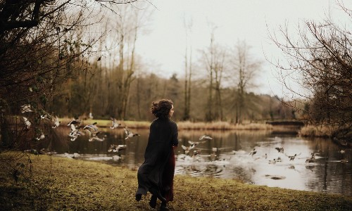 девушка бежит за летящими утками к озеру