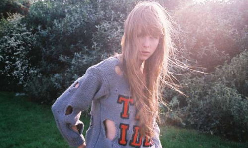 девушка с длинными волосами в разодранном свитере летом