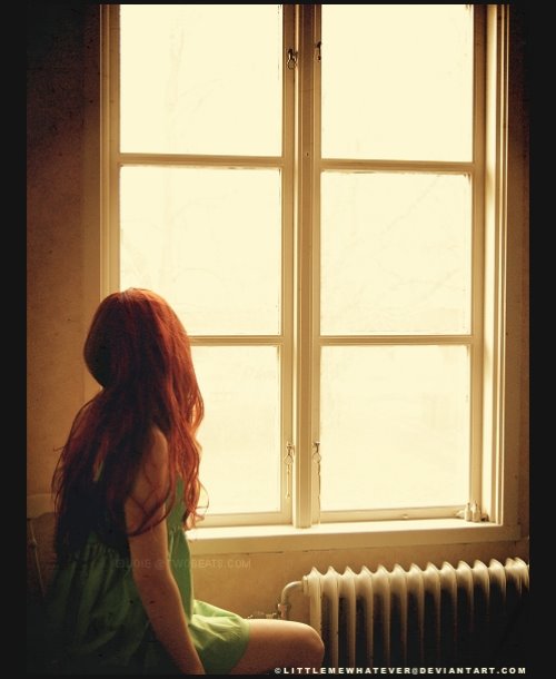Рыжая девушка в зеленом платье у окна с старыми радиаторами