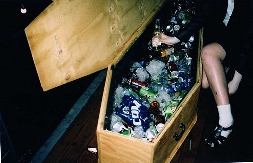 девушка достает алкоголь со льдом из гроба на тематической вечеринке