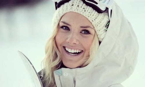 блондинка улыбается в белом лыжном костюме зимой