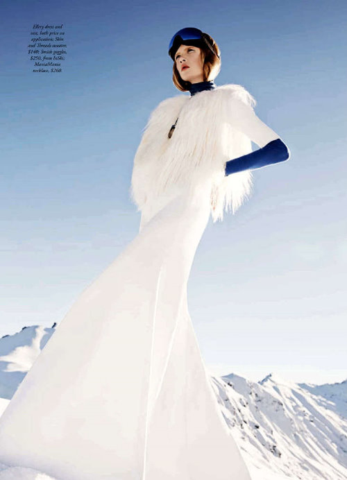 девушка в зимних горах в белой пушистой жилетке и синих очках